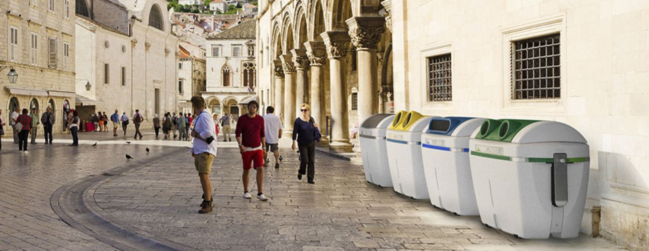 A row of urban small side loading garbage bin on a busy street  